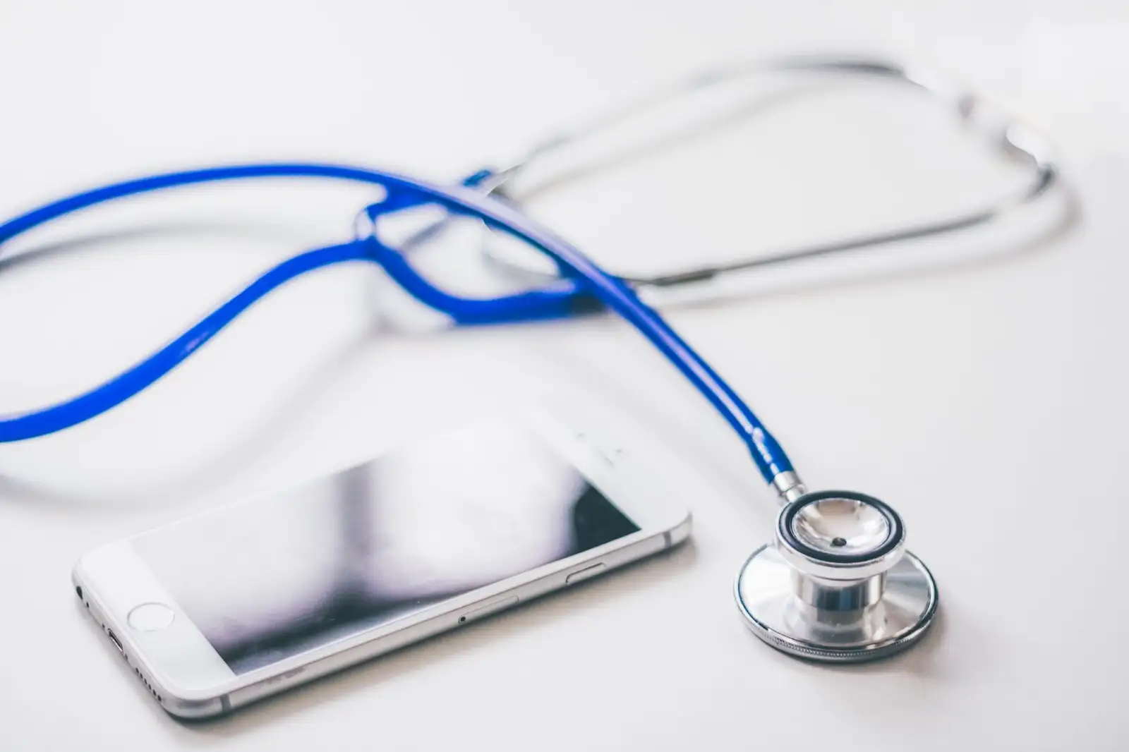 Smartphone next to a stethoscope on a white surface