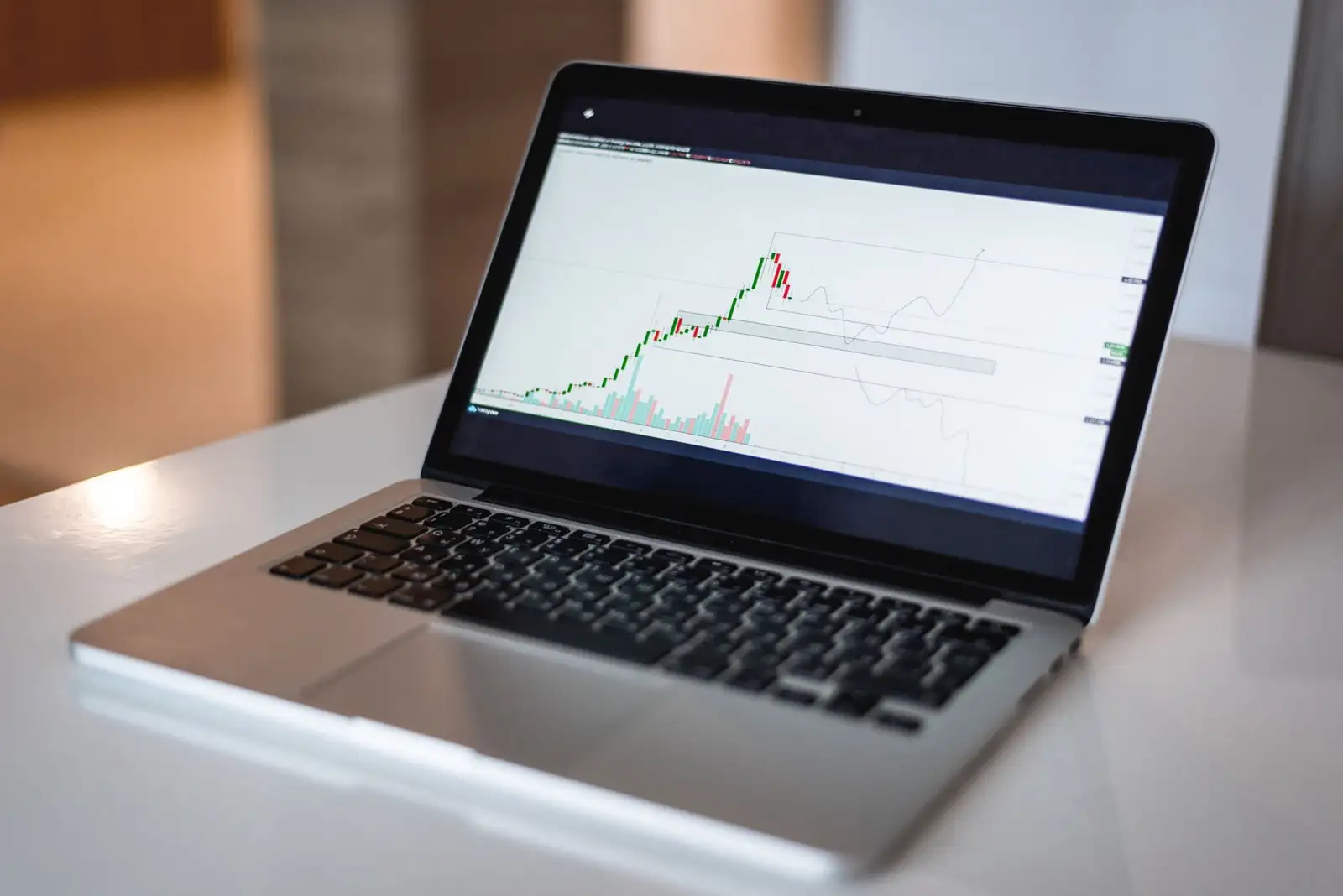 Laptop on a white table showing a financial chart