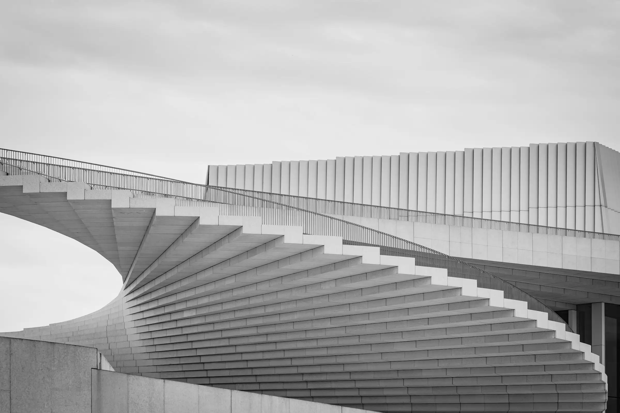 Spiral concrete staircase rising against a grey sky