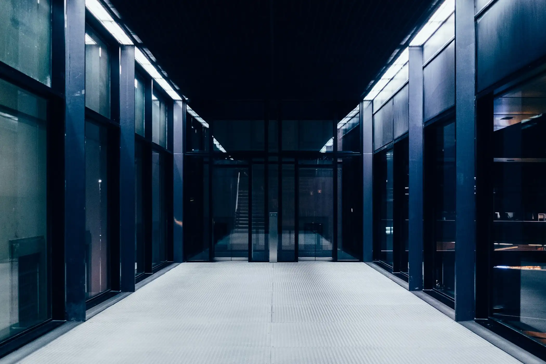 Long corridor lined with dark glass doors